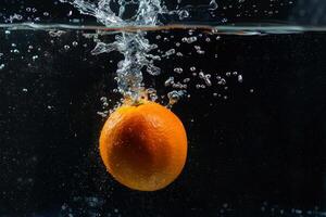 An orange is being dropped into water photo