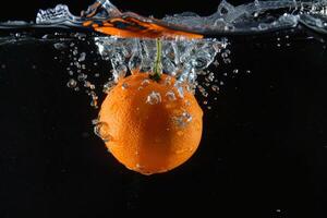 An orange is being dropped into water photo