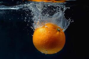 An orange is being splashed in water photo