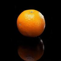 A single orange on a black surface photo