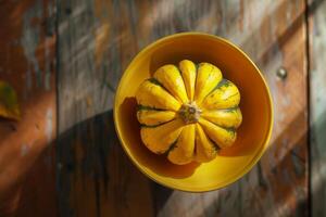 A yellow squash sitting in a bowl on a wooden table photo
