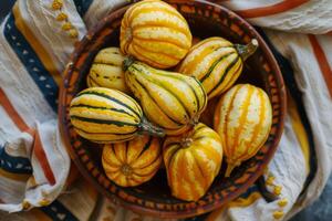 A bowl of yellow and green squash sitting on a table photo