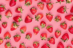 A large group of strawberries on a pink background photo