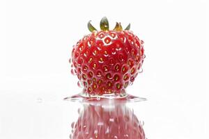 A strawberry is sitting in water with a reflection photo