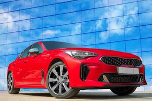 Red car on a blue sky background with white clouds. A stylish, modern, bright image of an avto mobile for design solutions. photo