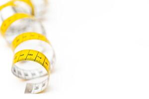 Yellow measuring tape on white background. Measurement of length and circumference. Lose weight and get fat. photo