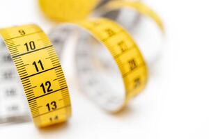 Yellow measuring tape on white background. Measurement of length and circumference. Lose weight and get fat. photo