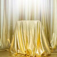 Stand draped in gold fabric. Abstract golden background. photo