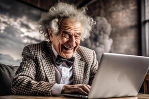 A gray-haired, broken elderly man in a red bow tie sits at a table with a laptop. He smiles and he is happy. photo