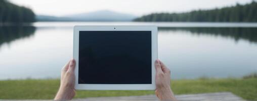 A woman's hand holding an ipad tablet with mountains in the background photo