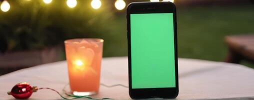 A green screen phone with christmas lights next to it photo