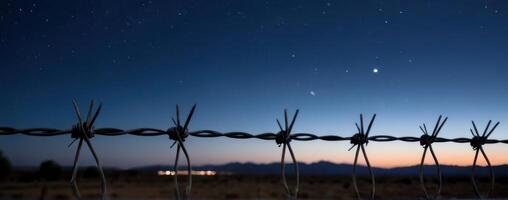 A barbed wire fence with stars in the sky photo