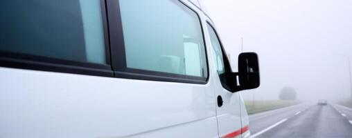 A white van is driving down the road in the fog photo