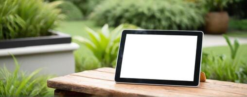 An ipad tablet sitting on a wooden table in the garden photo