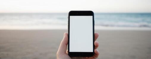 A woman holding an iphone on the beach photo