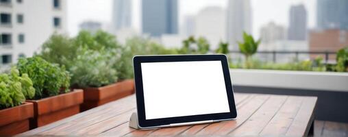 Tablet pc with blank screen on wooden table with city view photo