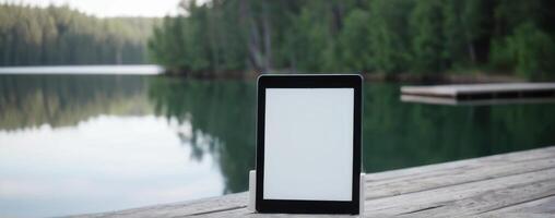 A smart phone sitting on the dock next to the lake photo
