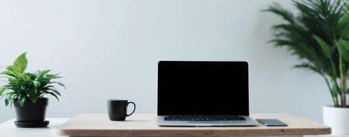 A laptop, phone, and plant on top of an empty wooden table photo
