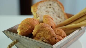 Homemade bread sticks, croissant and fresh toaster bread rotate in a wooden basket in kitchen video