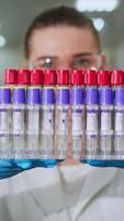 a cientista examina a teste tubos e leva notas. organizado teste tubos com científico amostras e substâncias dentro eles, pretendido para científico pesquisa video
