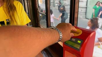 Italy Venice 10.07.2024 Person validating ticket on a public transportation machine. A close-up view of a person inserting a ticket into a red ticket validation machine on public transport. video