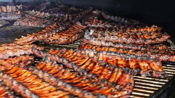 Grilled ribs cooking on a barbecue smoker. Rows of succulent, charred ribs cooking on a barbecue smoker. The ribs are coated in a rich glaze, with a combination of charred and tender meat. video
