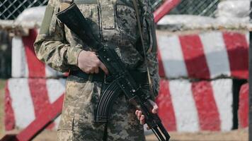 Soldier holding an assault rifle at a security checkpoint. A soldier in a camouflage uniform holding an assault rifle, standing at a security checkpoint. video