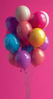Colorful balloons floating against a vibrant pink background for a festive celebration photo