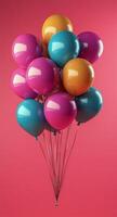 Colorful balloons floating against a vibrant pink background for a festive celebration photo