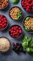 Fresh raspberries, blackberries, chickpeas, almonds, and basil arranged on a slate surface photo