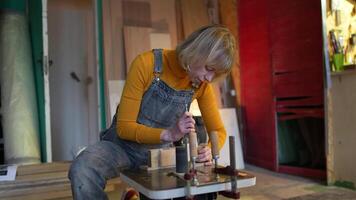 Dedicated woman carpenter fixes clamps on wooden beams before using grinding machine in workshop video