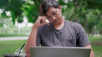 Serious man search for inspiration make decision feel lack of ideas, stressed from work, Sitting working in a park, Asian man thinking about work in nature, Working online. Worried, close up view. video