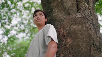 Asian man man thinking about life, looking forward with hope and listening to music with AirPods while walking in a park, Fresh air, Healthy lifestyle, Relaxation. video