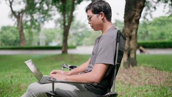 Programmer is writing code, typing on laptop keyboard. Programmer in casualwear developing new software writing program code on a laptop, work stress, working online, anxiety, working in a park. video