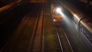 The train travels at night on the rails towards the camera. Top view video