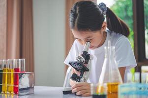little scientist looking through a microscope and test tubes filled with chemicals for learning about science and experiments. photo