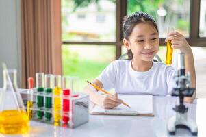little scientist looking through a microscope and test tubes filled with chemicals for learning about science and experiments. photo
