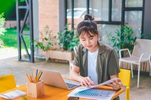 Freelance worker working on documents with graphs. and information about finances on laptops in cafes photo