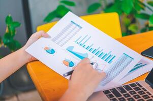 Freelance worker working on documents with graphs. and information about finances on laptops in cafes photo