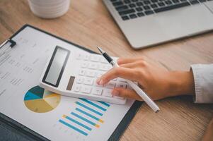 close up The business person is sitting on a calculator with a graph in the office of finance accounting concept photo