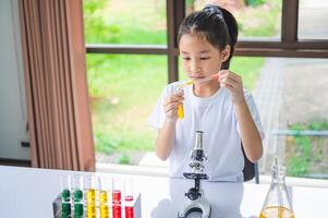 little scientist looking through a microscope and test tubes filled with chemicals for learning about science and experiments. photo
