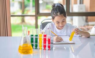 little scientist looking through a microscope and test tubes filled with chemicals for learning about science and experiments. photo