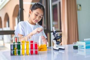 little scientist looking through a microscope and test tubes filled with chemicals for learning about science and experiments. photo