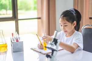 little scientist looking through a microscope and test tubes filled with chemicals for learning about science and experiments. photo
