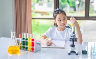 little scientist looking through a microscope and test tubes filled with chemicals for learning about science and experiments. photo