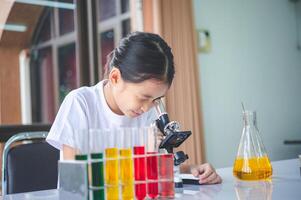 little scientist looking through a microscope and test tubes filled with chemicals for learning about science and experiments. photo