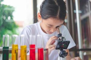 little scientist looking through a microscope and test tubes filled with chemicals for learning about science and experiments. photo