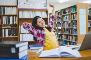 Students are relaxing after working on their laptops and searching for books to study, make reports, find useful information in the university room. photo