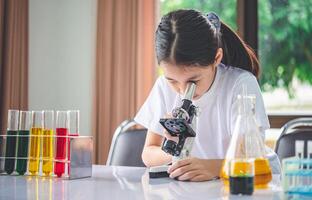 little scientist looking through a microscope and test tubes filled with chemicals for learning about science and experiments. photo