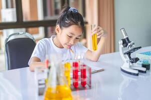 little scientist looking through a microscope and test tubes filled with chemicals for learning about science and experiments. photo